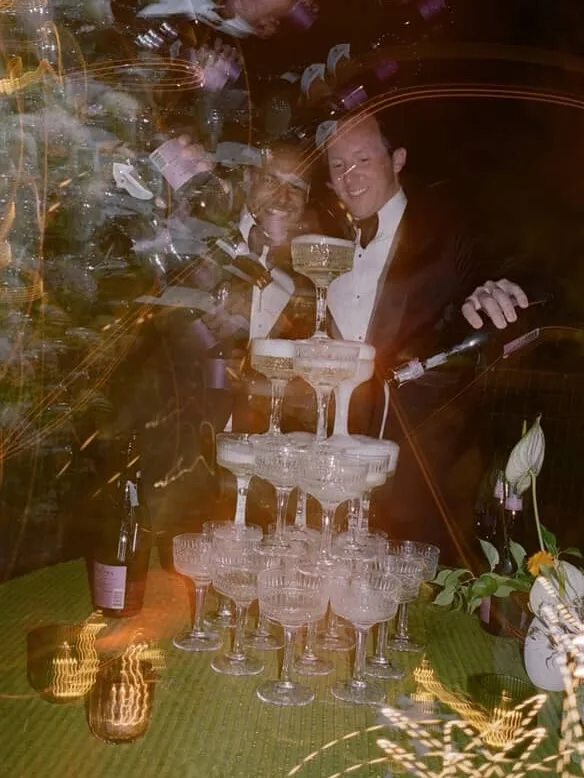 Bartender pouring sparkling wine into a champagne tower during evening wedding service