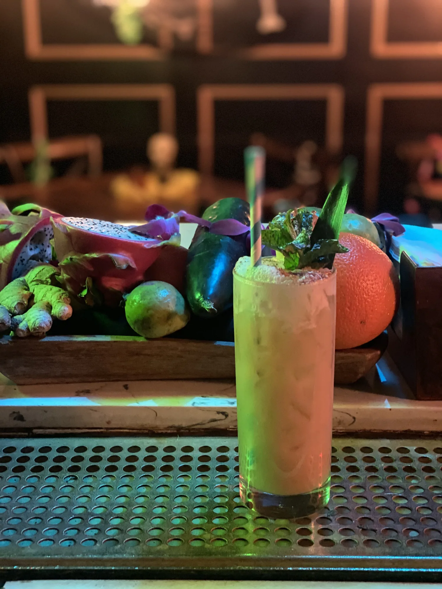 Colorful cocktails lined up across a nighttime bar.