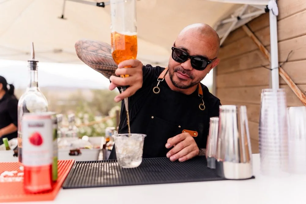 Bartender mixing an orange cocktail at a sunny outdoor event