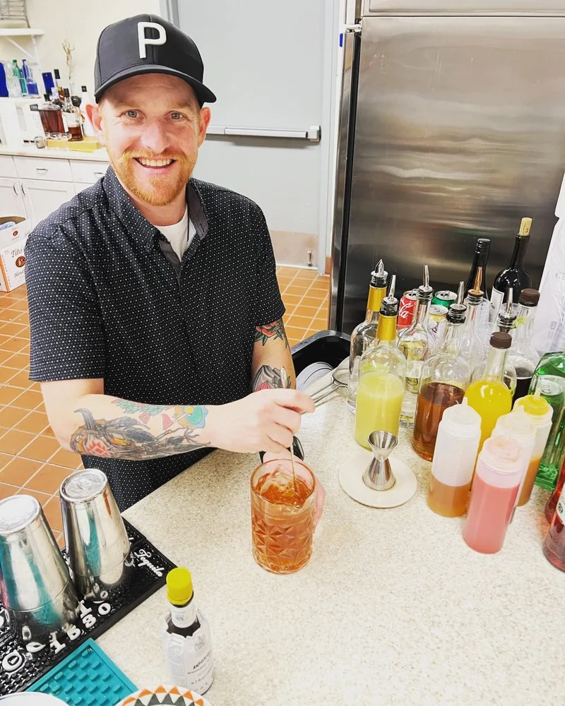Bartender pouring a cocktail at a busy service station