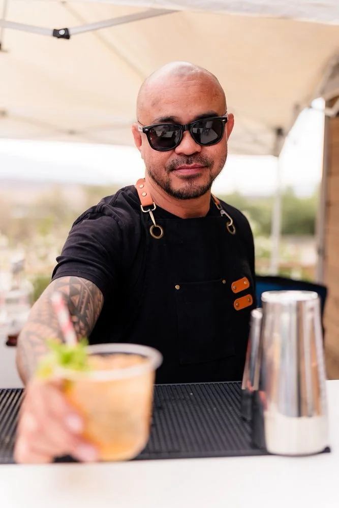 Bartender reaching across the mobile bar to hand a guest a fresh cocktail