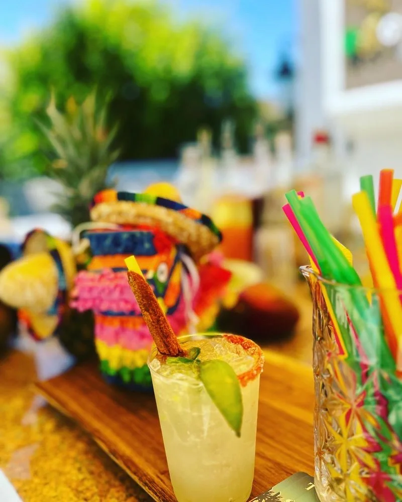 A lively display of tropical cocktails with fruit, flowers, and colorful straws