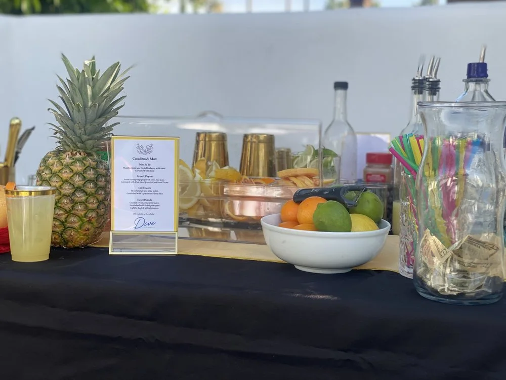 Complete mobile bar setup with spirits, fresh citrus, glassware, and a printed menu