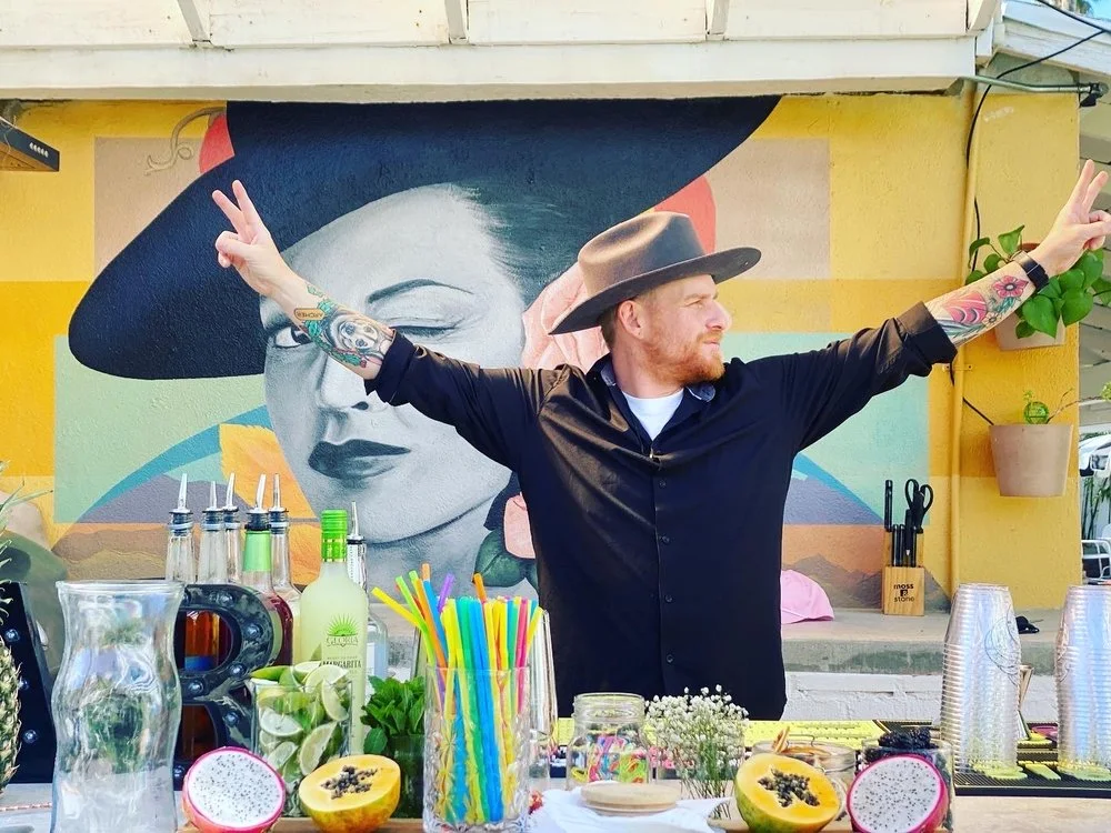Bartender celebrating behind a vibrant cocktail bar during a photo shoot