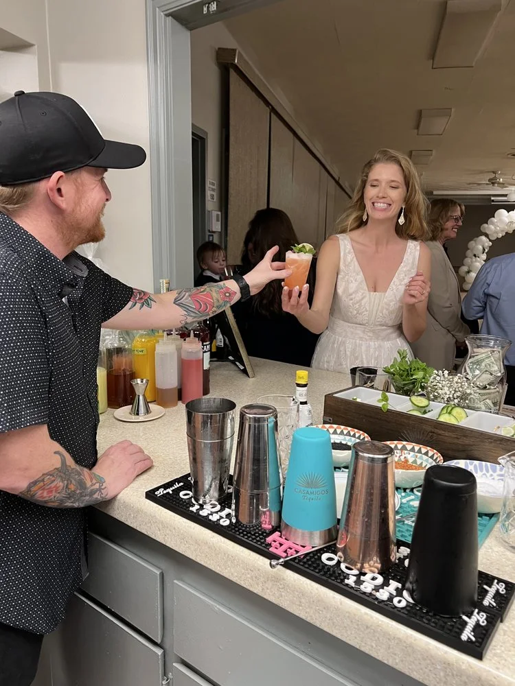Mobile bartender serving a guest from a polished indoor wedding bar
