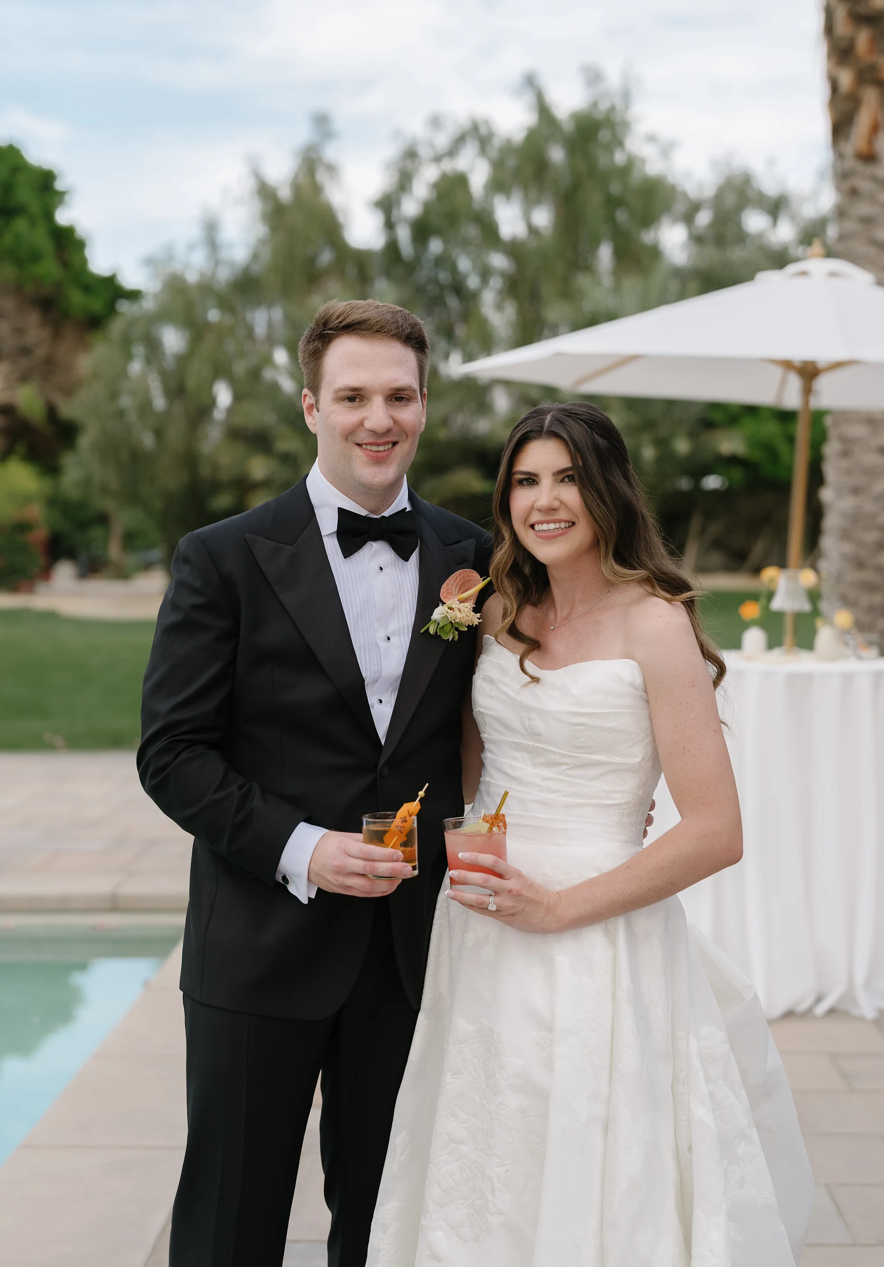 Newlyweds holding signature cocktails at their reception.