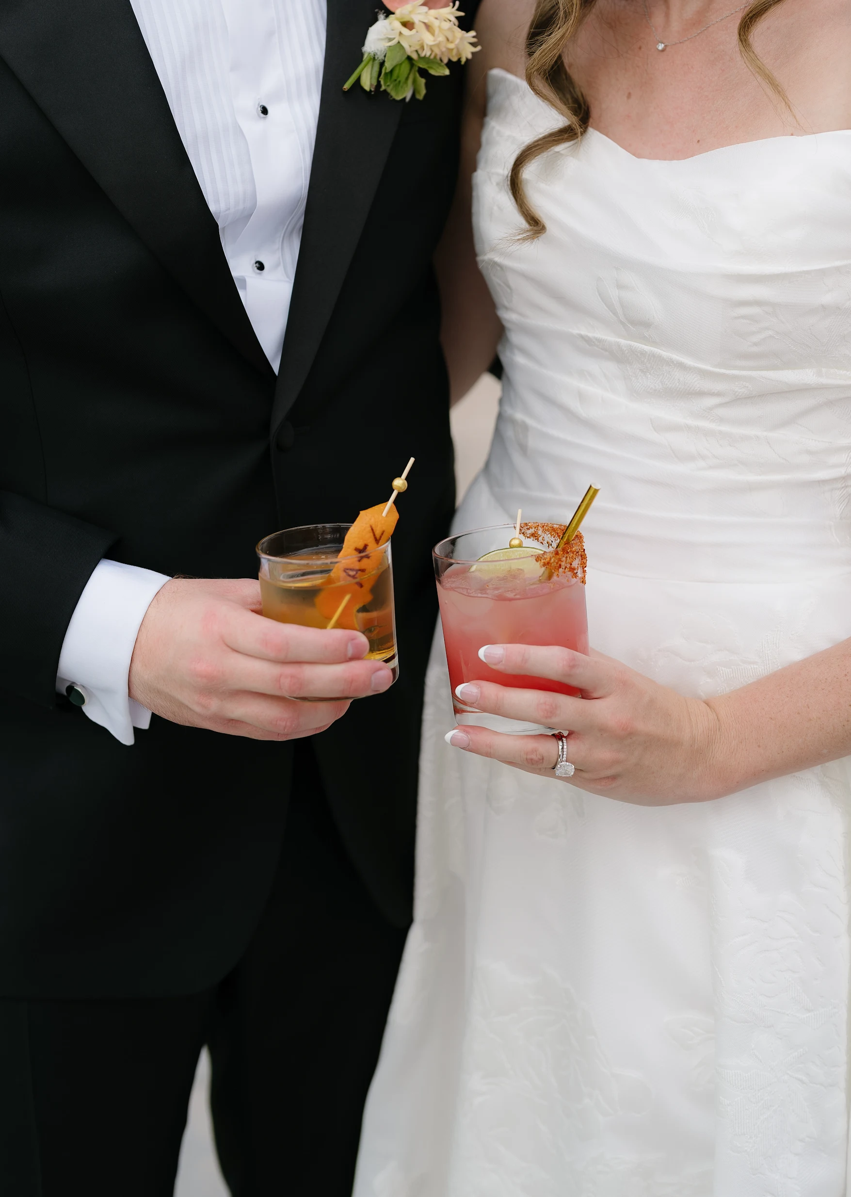 A couple holding two colorful wedding cocktails.