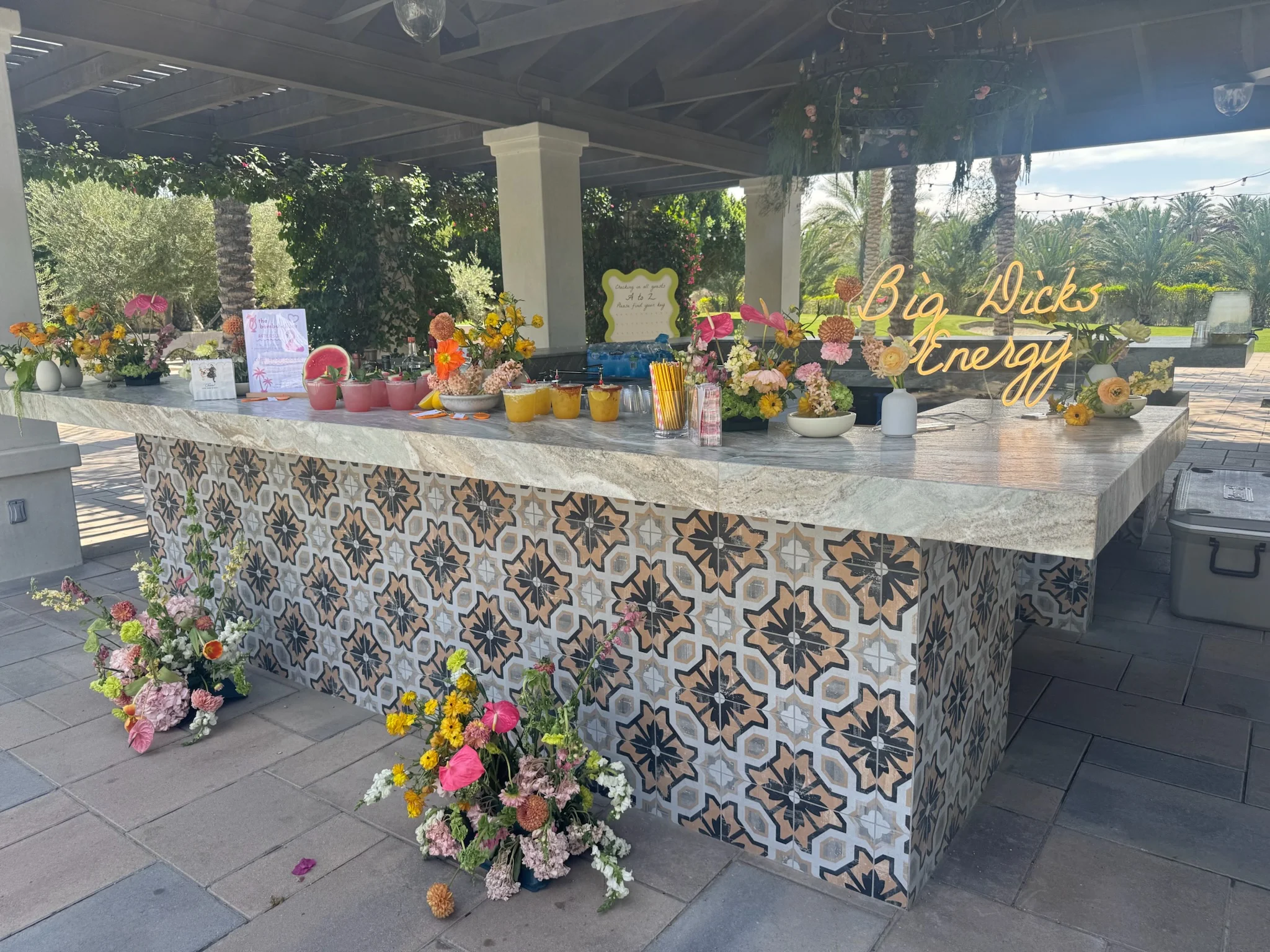 An outdoor wedding bar decorated with colorful flowers.