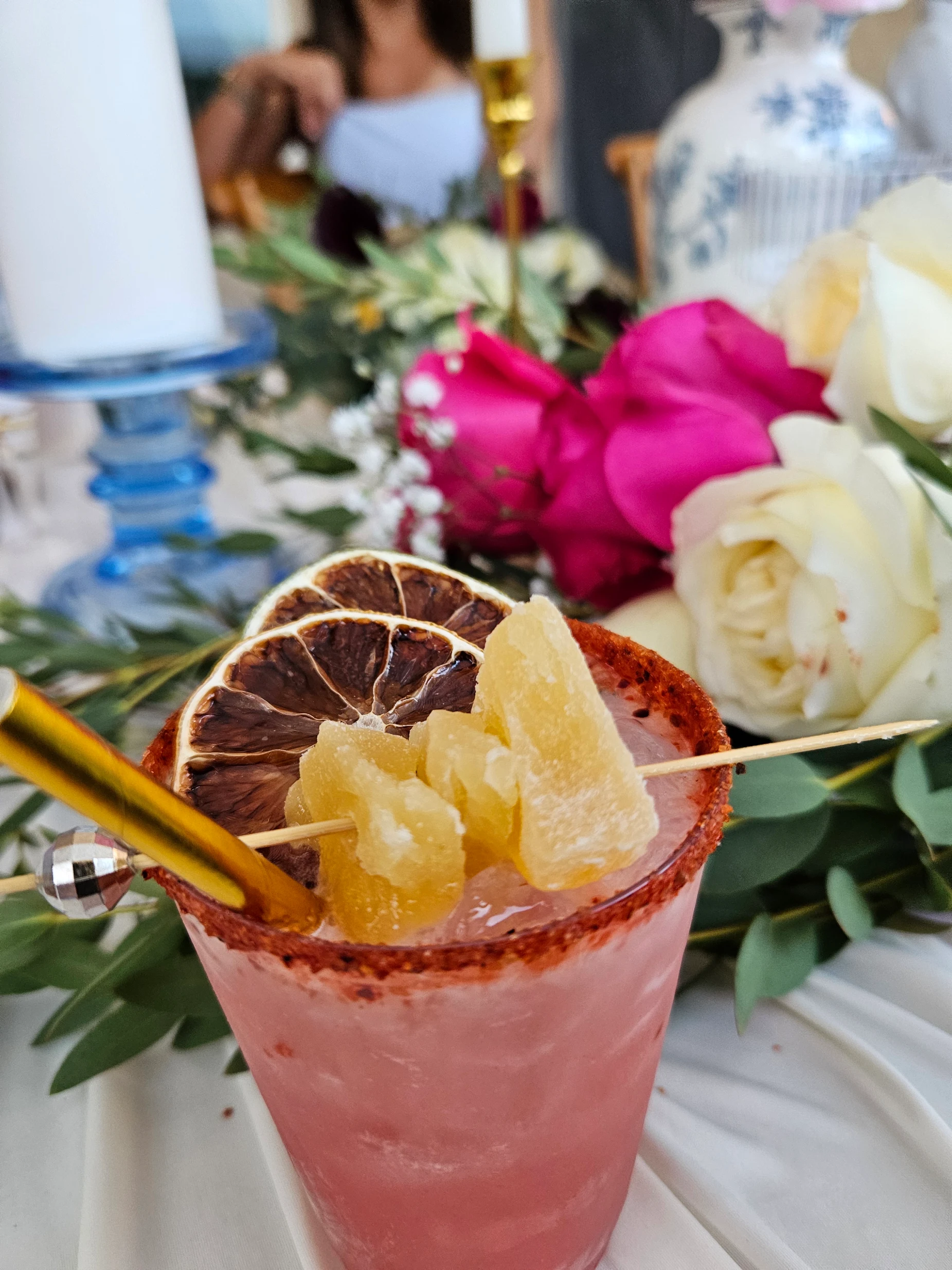 A garnished cocktail beside bright wedding flowers.