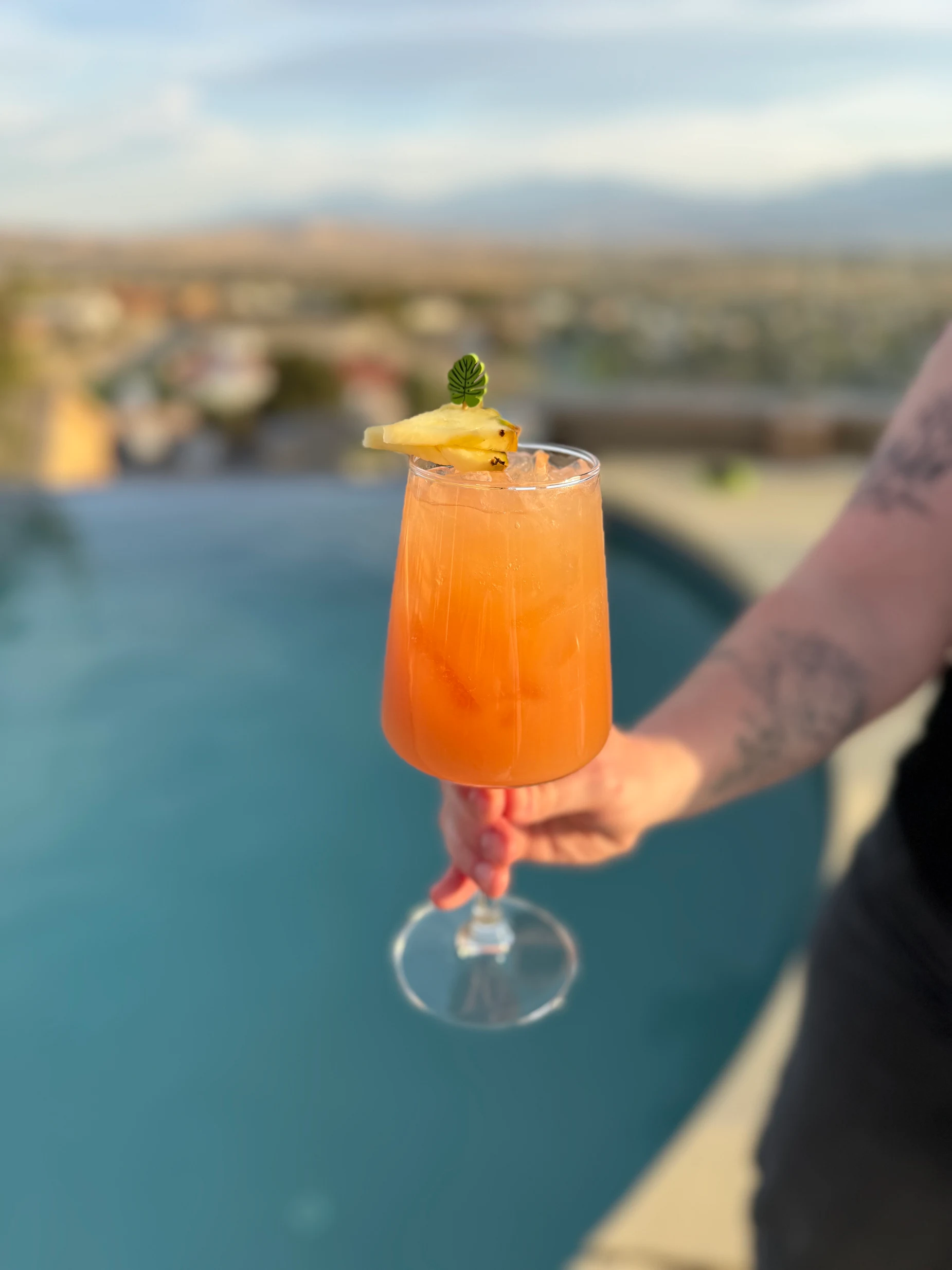 A guest holding an orange poolside cocktail.