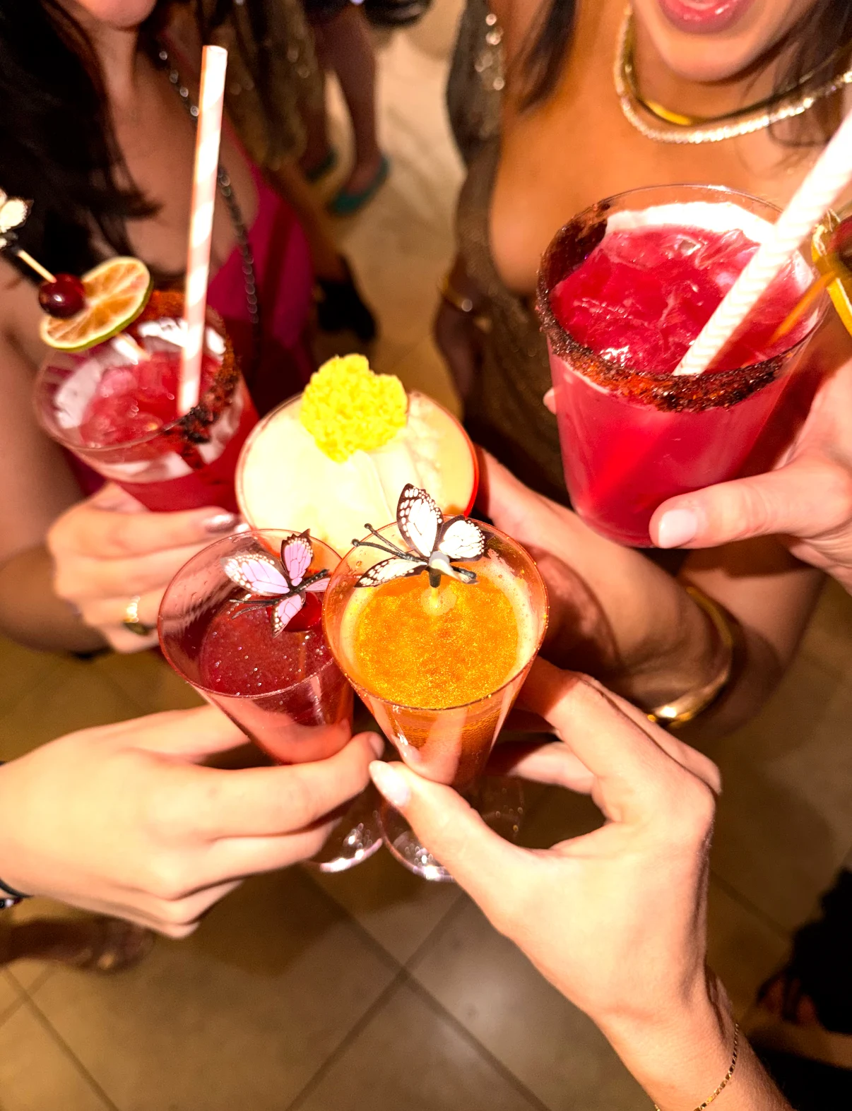 Friends raising colorful garnished cocktails together.