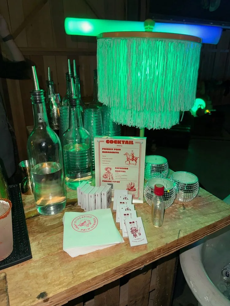 A cocktail bar and custom menu glowing under green event lighting.