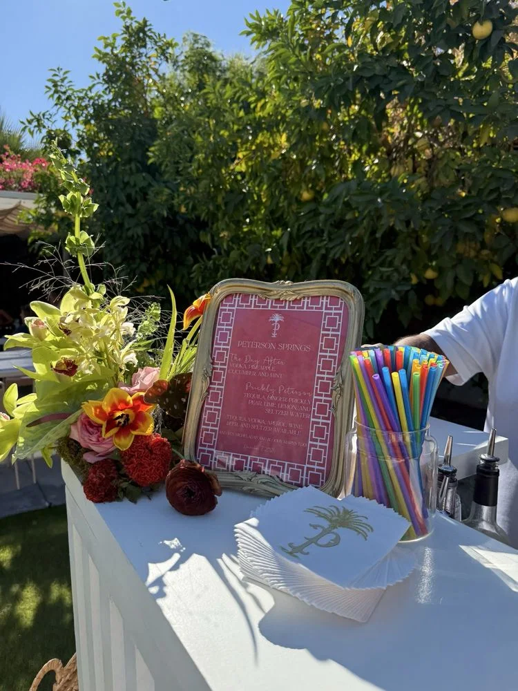 A floral mobile bar with a framed specialty cocktail menu.