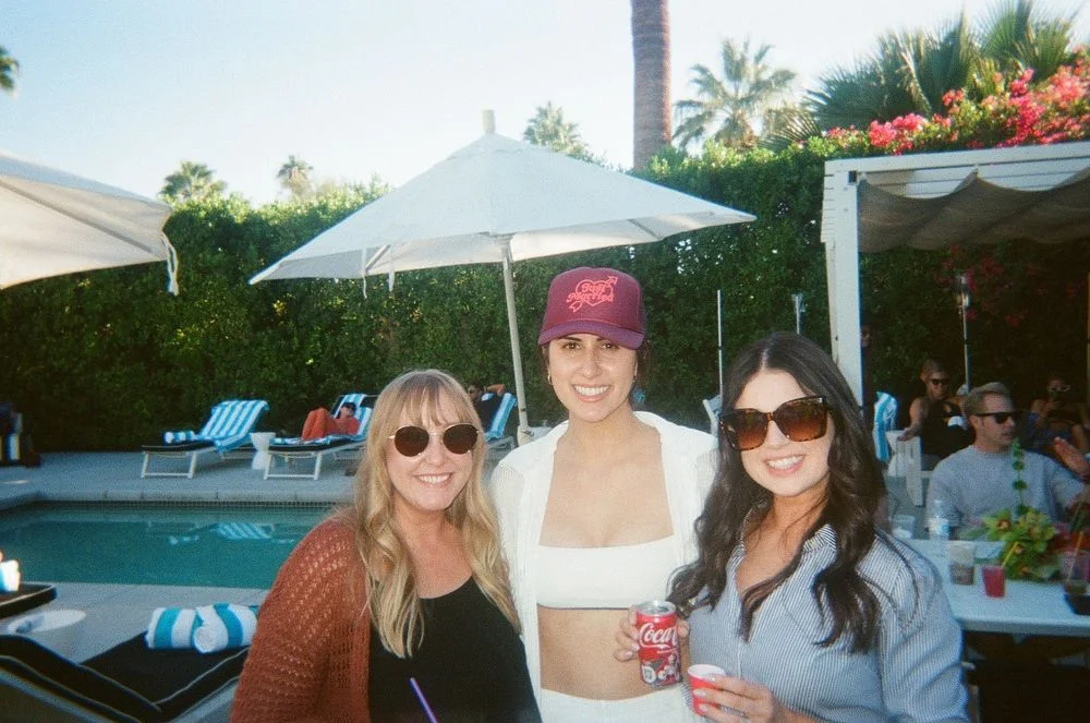 Three guests holding cocktails beside a Palm Springs pool.